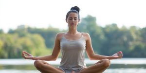 Person meditating peacefully by a tranquil lake.